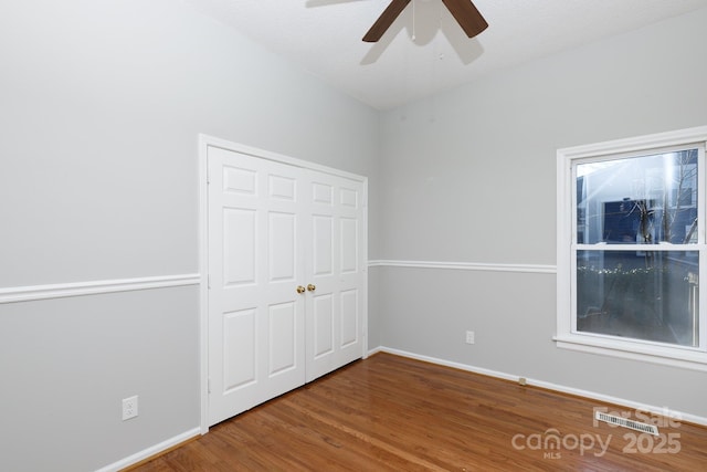 unfurnished bedroom featuring hardwood / wood-style floors, a closet, and ceiling fan