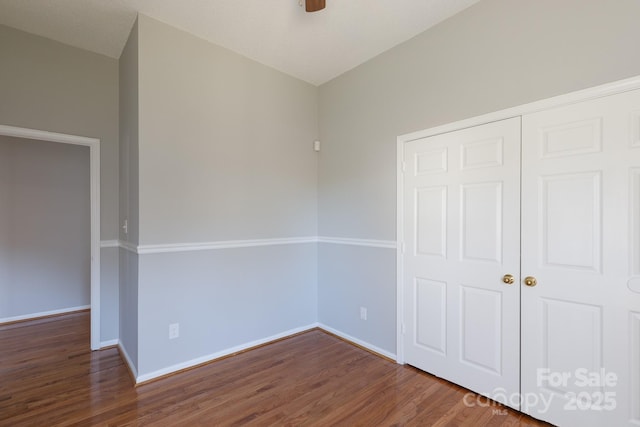 unfurnished bedroom featuring dark wood-type flooring, a closet, lofted ceiling, and ceiling fan