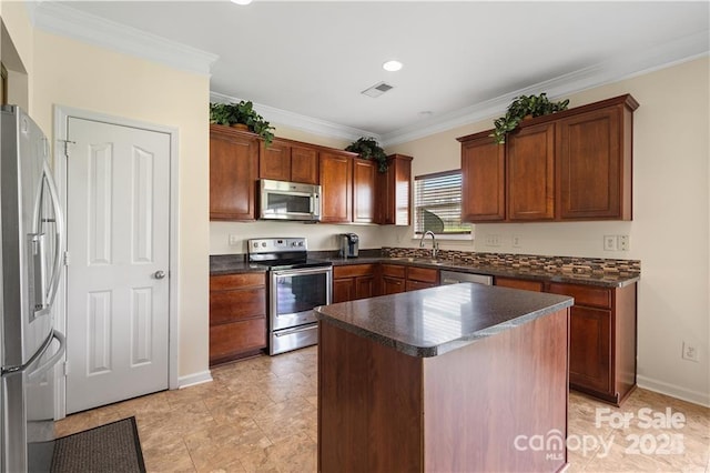 kitchen with appliances with stainless steel finishes, a center island, crown molding, and sink