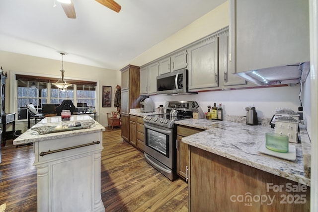 kitchen with light stone counters, decorative light fixtures, stainless steel appliances, and dark hardwood / wood-style floors