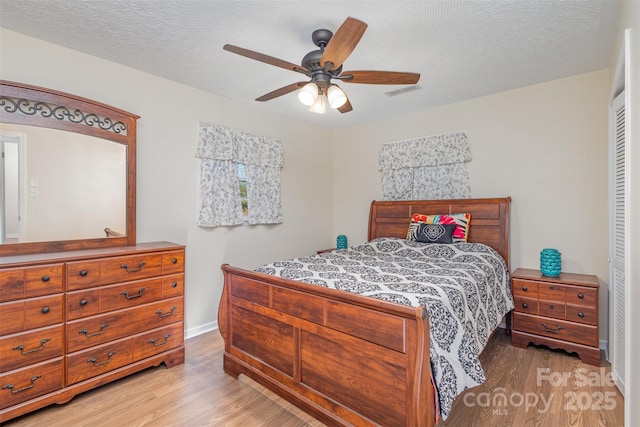 bedroom featuring ceiling fan, a closet, a textured ceiling, and light wood-type flooring