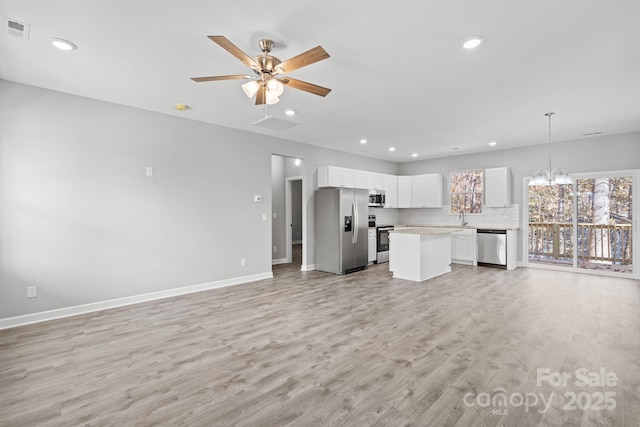 unfurnished living room with ceiling fan with notable chandelier, light wood-type flooring, and sink