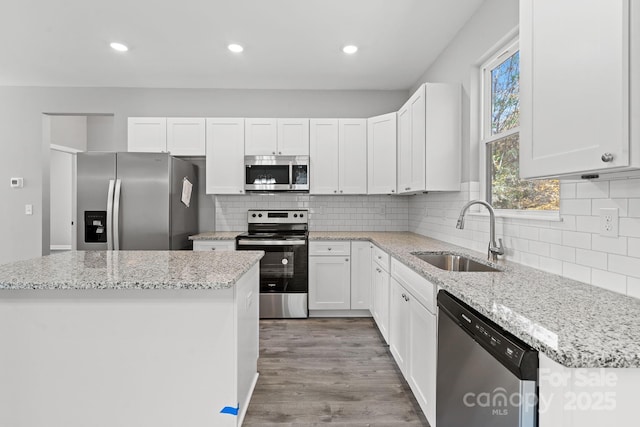 kitchen featuring backsplash, stainless steel appliances, sink, white cabinets, and a kitchen island