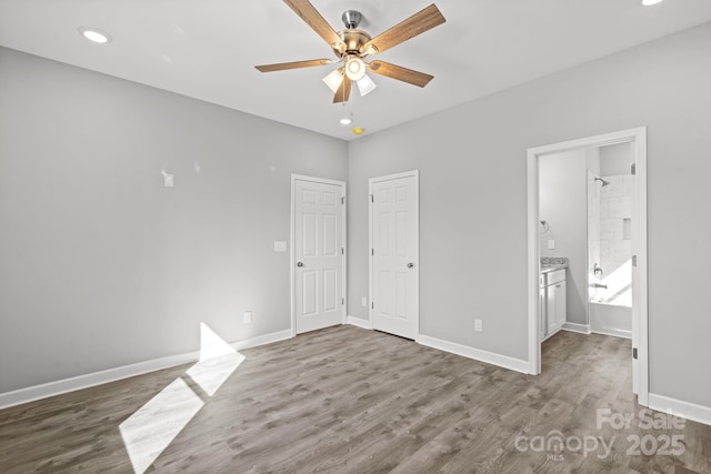 unfurnished bedroom featuring connected bathroom, dark hardwood / wood-style floors, and ceiling fan