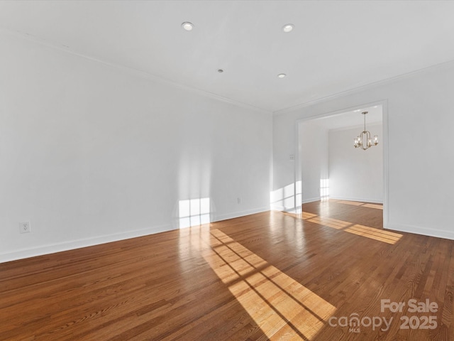 unfurnished room with hardwood / wood-style flooring, crown molding, and a notable chandelier