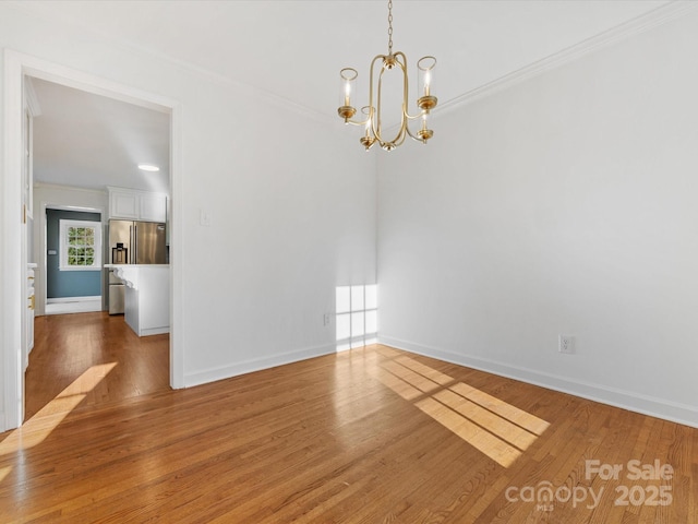 spare room with hardwood / wood-style flooring, a notable chandelier, and crown molding