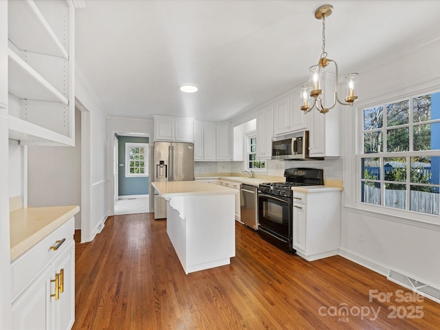 kitchen featuring dark wood-type flooring, hanging light fixtures, white cabinets, a kitchen island, and appliances with stainless steel finishes