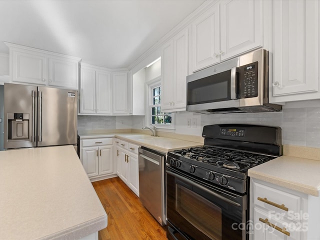 kitchen featuring sink, stainless steel appliances, backsplash, white cabinets, and light wood-type flooring