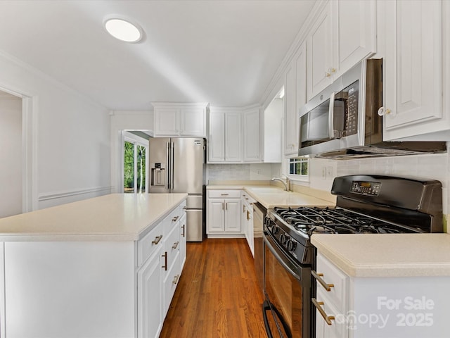 kitchen featuring a center island, stainless steel appliances, dark hardwood / wood-style flooring, crown molding, and white cabinets