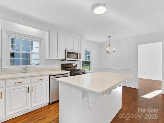 kitchen with a center island, white cabinetry, hanging light fixtures, and appliances with stainless steel finishes