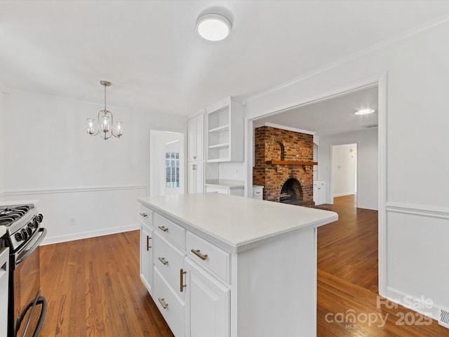 kitchen with stove, dark hardwood / wood-style flooring, decorative light fixtures, white cabinets, and a center island