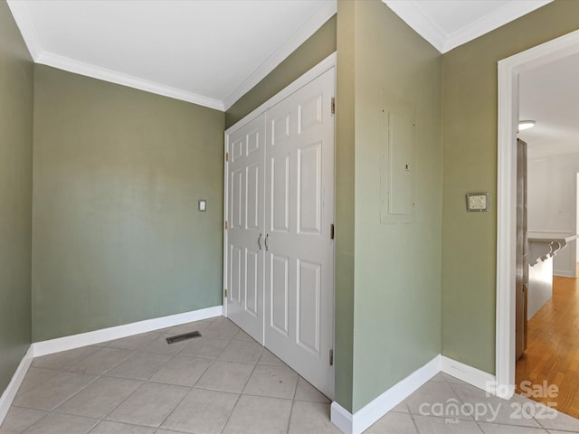 hall with light tile patterned floors, crown molding, and electric panel