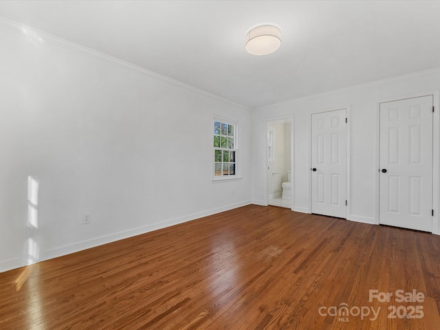 unfurnished bedroom featuring wood-type flooring, connected bathroom, and ornamental molding