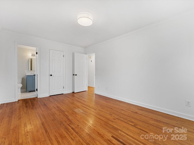 unfurnished bedroom with connected bathroom, light hardwood / wood-style floors, and crown molding