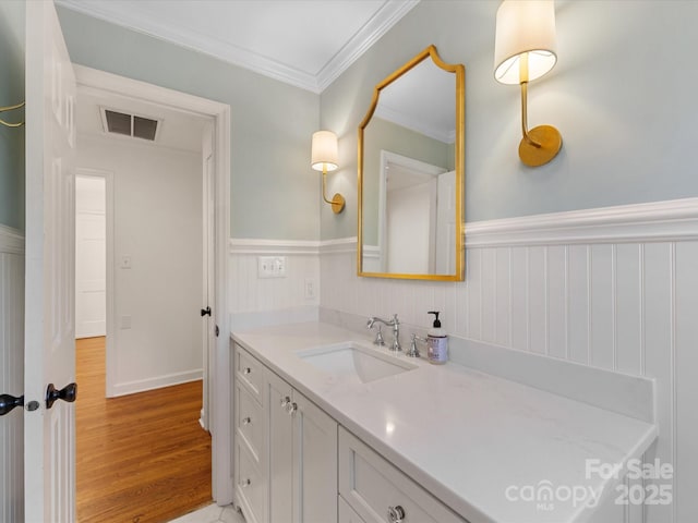 bathroom featuring wood-type flooring, vanity, and ornamental molding