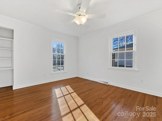 empty room featuring ceiling fan, built in features, wood-type flooring, and ornamental molding