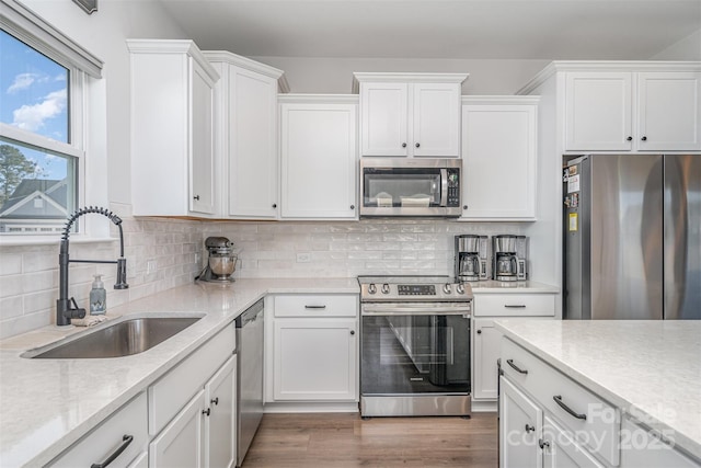 kitchen featuring sink, stainless steel appliances, wood-type flooring, decorative backsplash, and white cabinets