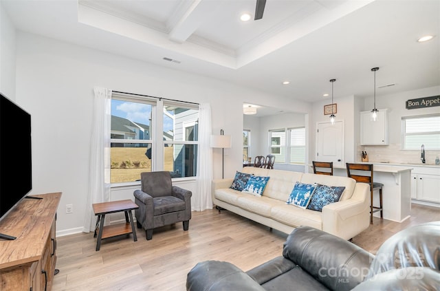 living room featuring light hardwood / wood-style flooring, beamed ceiling, plenty of natural light, and sink