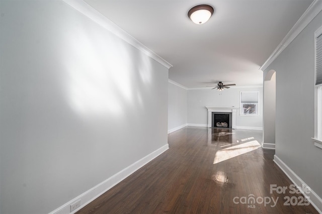 unfurnished living room featuring a brick fireplace, dark wood-type flooring, ornamental molding, and ceiling fan