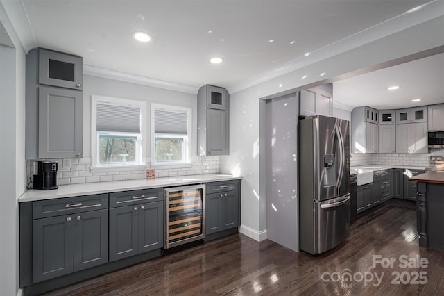 kitchen with gray cabinets, appliances with stainless steel finishes, beverage cooler, and backsplash