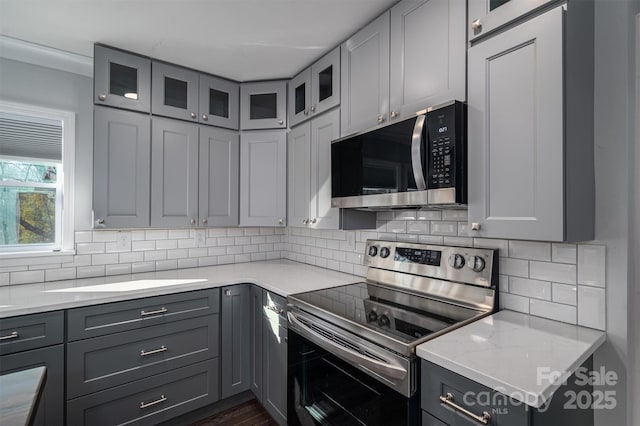 kitchen with light stone countertops, gray cabinets, and stainless steel appliances