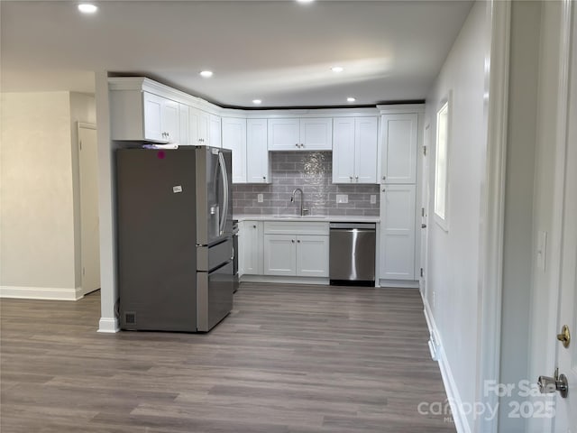 kitchen with wood-type flooring, stainless steel appliances, white cabinetry, and sink