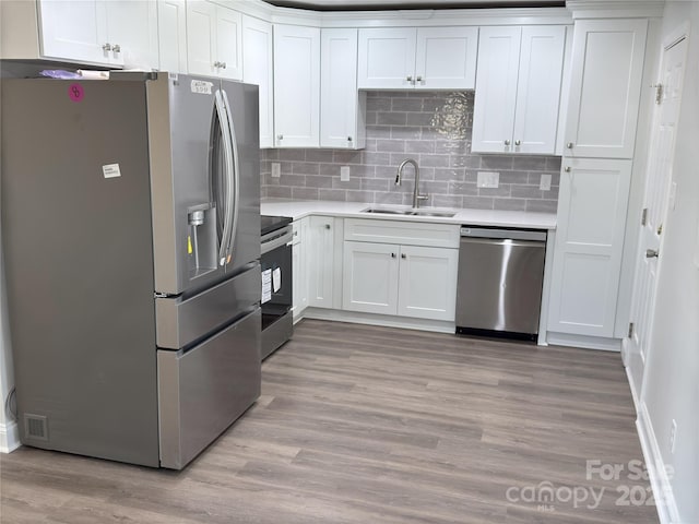 kitchen with sink, stainless steel appliances, light hardwood / wood-style floors, decorative backsplash, and white cabinets