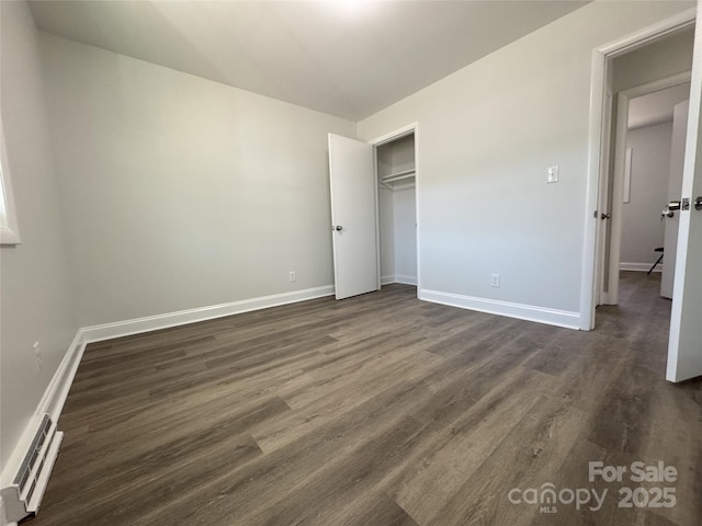 unfurnished bedroom featuring a closet, dark hardwood / wood-style flooring, and a baseboard radiator