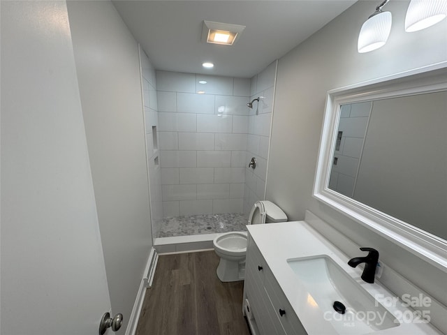 bathroom featuring tiled shower, wood-type flooring, vanity, and toilet