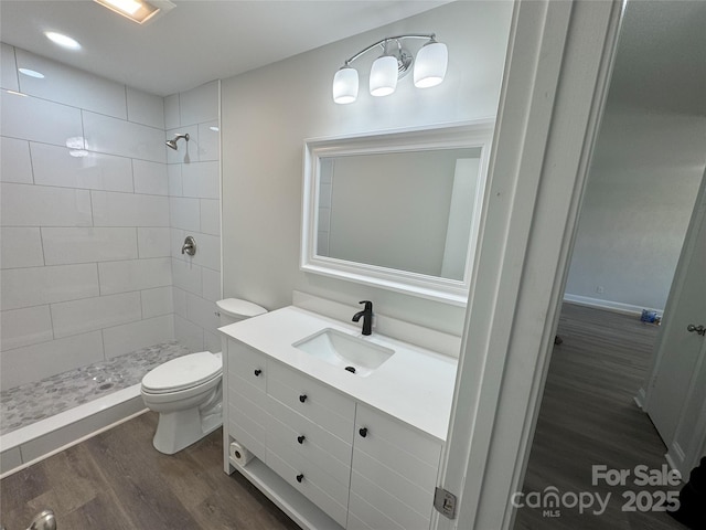 bathroom featuring tiled shower, wood-type flooring, vanity, and toilet