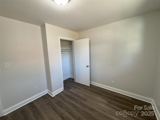 unfurnished bedroom with a closet and dark wood-type flooring