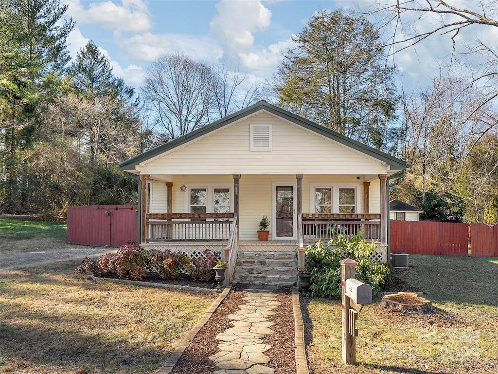 view of front facade featuring covered porch, central AC unit, and a front yard