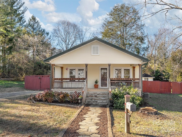 view of front facade featuring covered porch, central AC unit, and a front yard