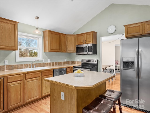 kitchen with pendant lighting, a center island, sink, vaulted ceiling, and appliances with stainless steel finishes