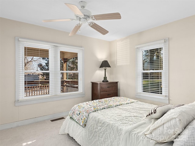 carpeted bedroom featuring multiple windows and ceiling fan