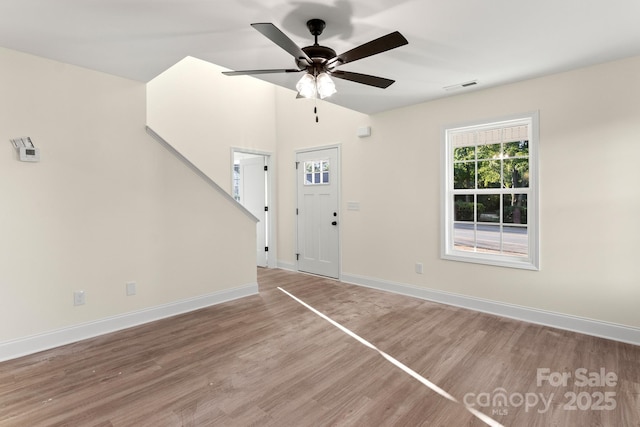 interior space with ceiling fan, lofted ceiling, wood finished floors, visible vents, and baseboards