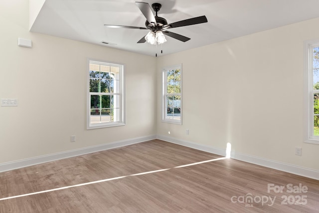 spare room with ceiling fan, wood finished floors, visible vents, and baseboards