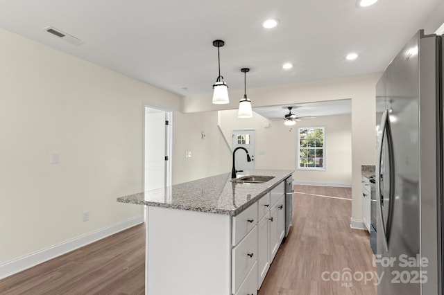 kitchen featuring visible vents, appliances with stainless steel finishes, light wood-style floors, white cabinetry, and a sink