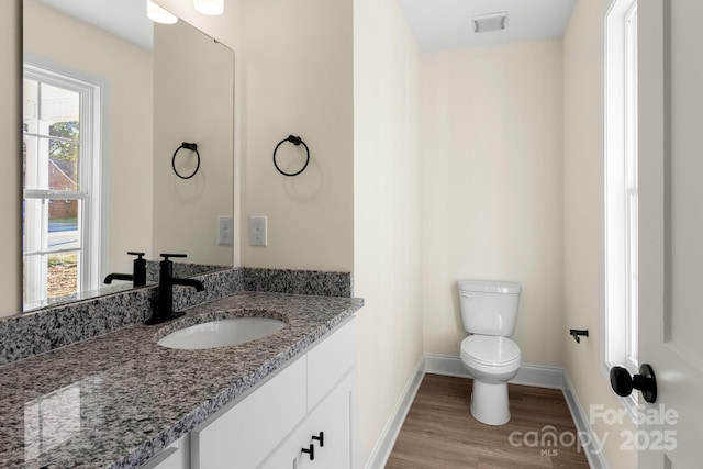 bathroom featuring visible vents, toilet, vanity, wood finished floors, and baseboards