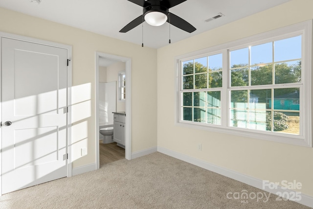 unfurnished bedroom with light carpet, multiple windows, visible vents, and baseboards