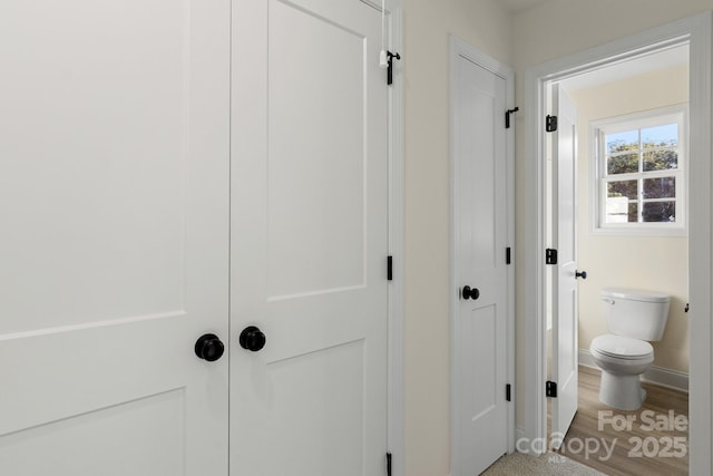 bathroom featuring a closet, baseboards, toilet, and wood finished floors