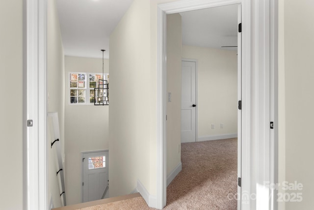 corridor featuring plenty of natural light, baseboards, carpet flooring, and an upstairs landing