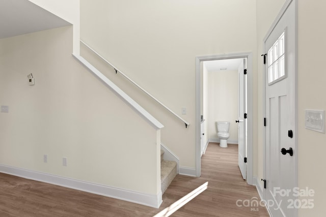 staircase featuring wood finished floors and baseboards