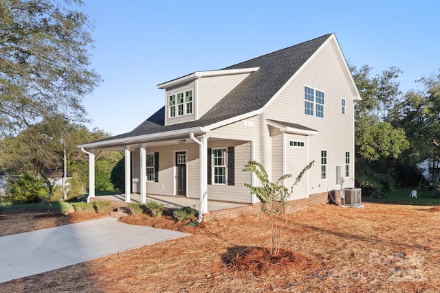 view of front of home with a shingled roof, cooling unit, and a porch