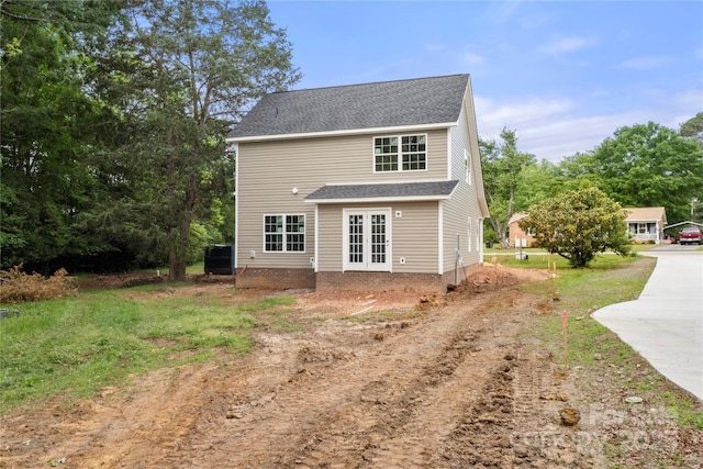 view of side of property with concrete driveway, french doors, and a shingled roof