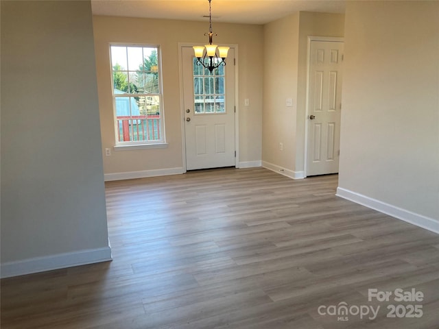 unfurnished dining area with a chandelier and light hardwood / wood-style flooring