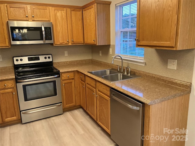 kitchen featuring appliances with stainless steel finishes, light hardwood / wood-style floors, and sink