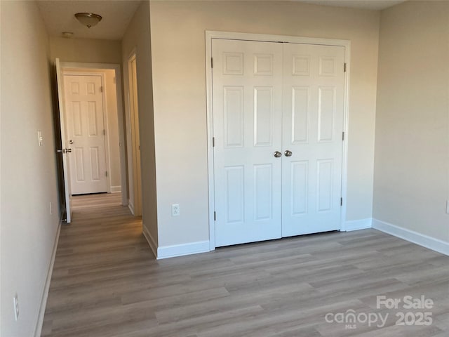 unfurnished bedroom with light wood-type flooring and a closet