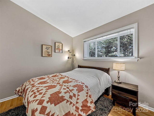 bedroom with lofted ceiling and wood-type flooring