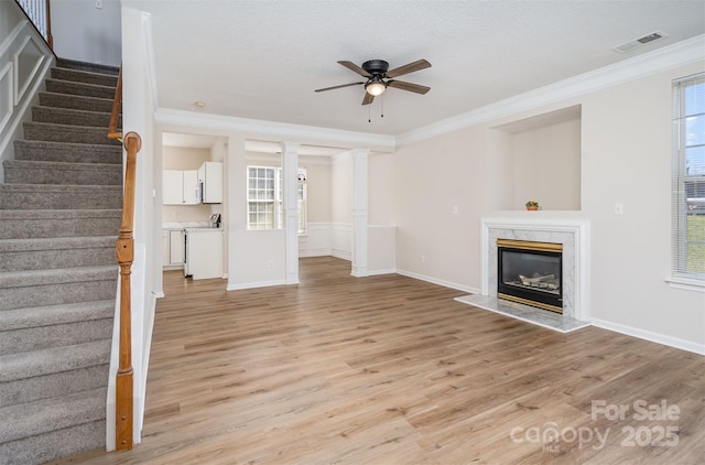 unfurnished living room featuring a healthy amount of sunlight, visible vents, and crown molding